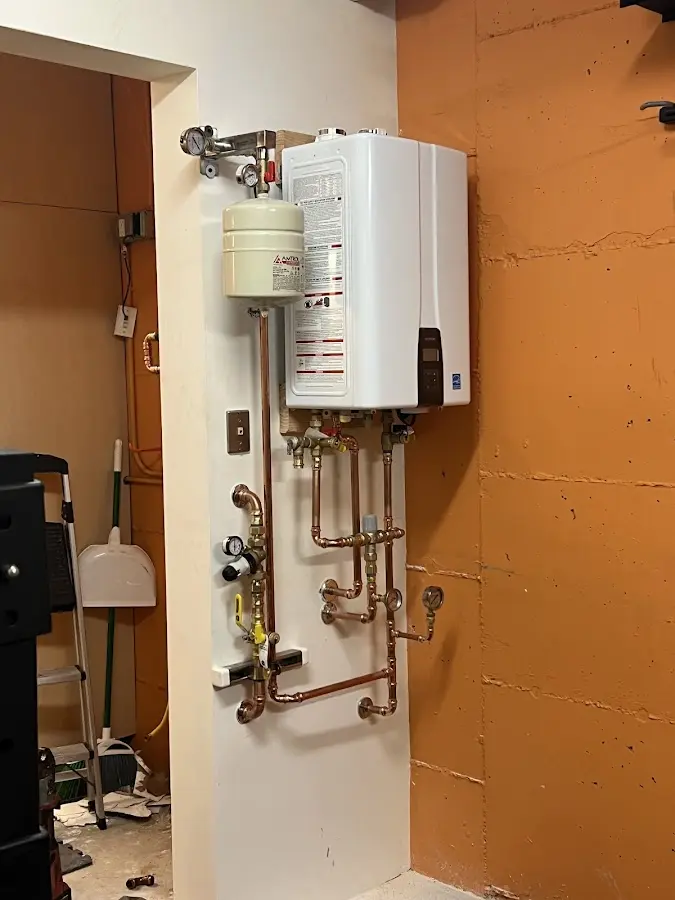 Plumbing technician inspecting water heater connections in Andover